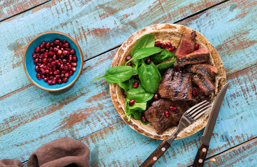 Wall Mural - Close up plate with grilled steak, spinach leaves and pomegranate