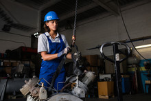 Female Mechanic Operating A Hoist To Lift A Compressor Engine