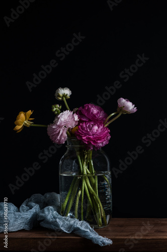 Fotografie, Obraz Dark and moody image of colorful ranunculus flowers