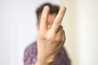 © bevisphoto - Mann zeigt zwei Finger am ausgestreckten Arm