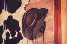 Cowboy Hat Hanging On Brick Wall.
