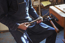 Midsection Of Carpenter Holding Hammer At Workshop