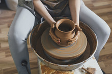 Midsection Of Female Potter Making Pot With Clay In Workshop