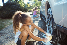 Girls Washing Car In Driveway