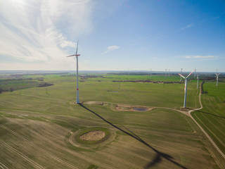 aerial view panorama of green agriculture fields with blue sky and wind turbines in the background