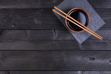 Wall Mural - Background for sushi. Soy sauce, chopsticks on black stone. Top view with copy space