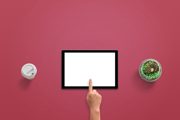 Poster - Tablet with isolated white display for mockup. Woman hand touch screen. Top view of red desk. Coffee and plant beside.