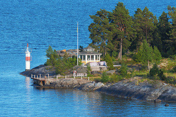 Wall Mural - Archipelago of Stockholm as seen from passenger ship with a small yellow recreation house and lighthouse