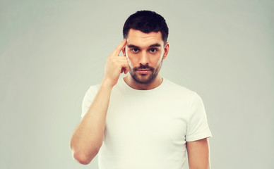 Wall Mural - man with finger at temple over gray background