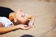 © raisondtre - young beautiful brunette girl in black dress relaxes on the sand, eyes closed and hands outstretched palms up, close-up