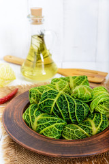 Wall Mural - Leaves of Savoy cabbage stuffed with minced meat and rice in a clay bowl on a light background.