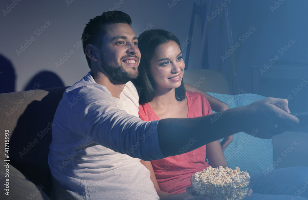 Young couple watching TV at home