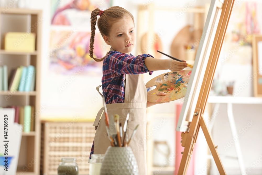 Cute little artist painting picture in studio