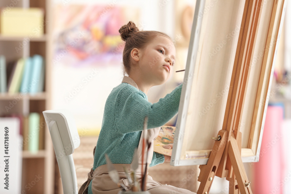 Cute little artist painting picture in studio
