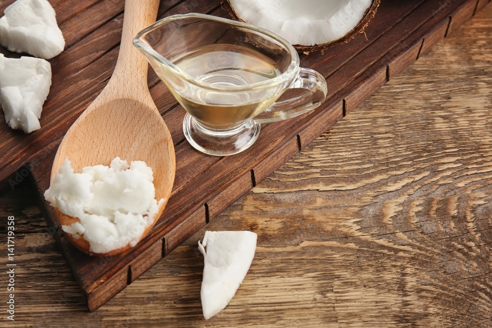 Coconut and kitchenware with fresh oil on wooden board