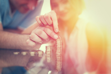 Young couple building money column from coins in sunset