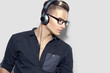 Handsome young man enjoying music on headphones over gray background