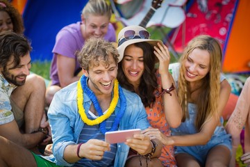 Wall Mural - Group of friends using mobile phone at campsite