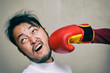 funny face man getting punch in face with boxing glove against gray background