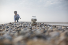Boy Collecting Pebbles On Beach
