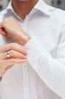 © belyjmishka - Man buttons cuff-link on French cuffs sleeves luxury white shirt. Close up of a businessman showing a shirt cuff.