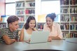 © WavebreakMediaMicro - Happy students using laptop in library