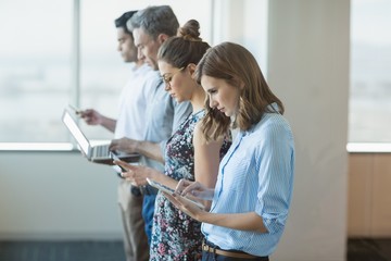 Wall Mural - Business colleagues standing in a row using tablet