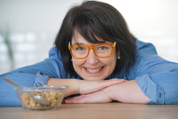 Dark-haired woman in kitchen eating cereals