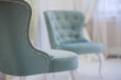 Two turquoise classic luxury armchair in white room. One mint chair standing back to camera. Close-up.