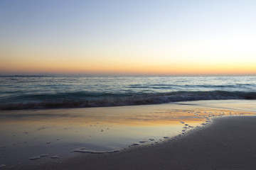Wall Mural - Sunrise on the beach. The caribbean sea is about to wake up. Sun coming up behind the horizon. Long exposure image. Focus point on the right side of the image.