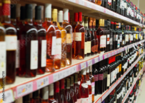 Cuadros en Lienzo Blurred image of shelves with alcoholic drinks in supermarket.