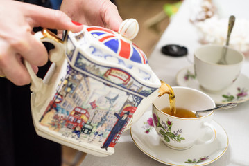 tea poured into tea cup with british symbols