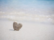 Stone heart shape standing on summer beach sand