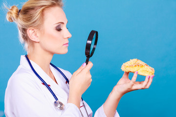 Doctor with magnifying glass examining sweet food