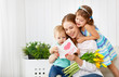 Happy mother's day! Children congratulates moms and gives her a postcard and flowers