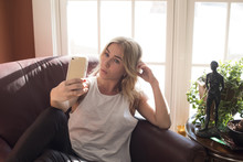 Woman Taking Selfie While Sitting On Armchair At Home