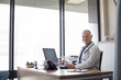 © Cavan Images - Portrait of smiling doctor working at desk by window in hospital