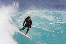 A Surfer Carves Down The Face Of A Blue Wave.