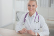 © lenets_tan - Beautiful young smiling female doctor sitting at the desk and writing.