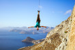 Cheerful rock climber swinging on rope upside down