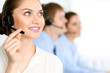 © rogerphoto - Call center operators. Focus at brunette business woman in headset