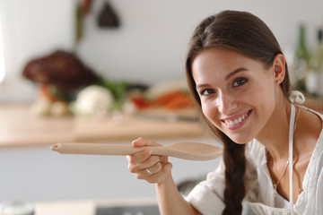 Wall Mural - Cooking woman in kitchen with wooden spoon