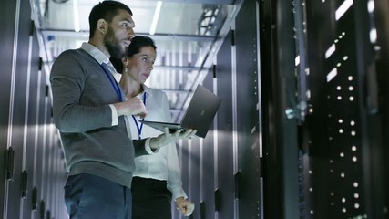 Wall Mural - Male and Female Server Engineers Work on a Laptop in Data Center. He Opens Server Cabinet. Shot on RED EPIC-W 8K Helium Cinema Camera.