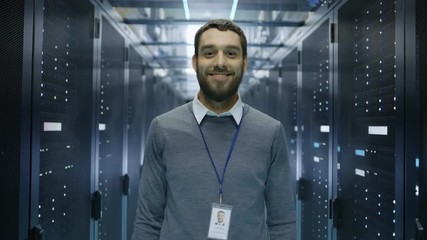 Wall Mural - IT Engineer Walks Into Focus  and Smiles in Data Center Full of Rack Servers. Shot on RED EPIC-W 8K Helium Cinema Camera.