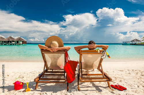 Couple in loungers on beach at Maldives Billede på lærred