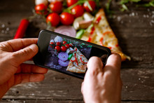 Man Using Smartphone To Take Picture Of Slice Of Pizza.