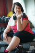 © goodluz - Overweight woman at the gym lifting dumbbells
