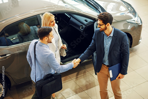 Fotografía Young couple shaking hands with sales agent after a successful car buying