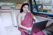 © Creativa Images - Indian female entrepreneur with laptop in car