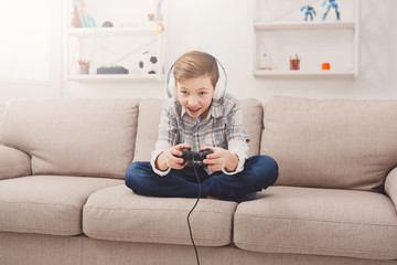 Excited teenage boy playing video game at home